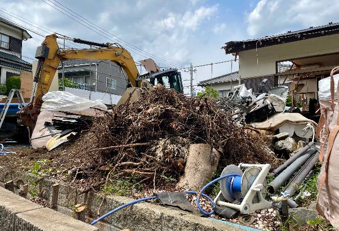 家をショベルカーで解体している写真。