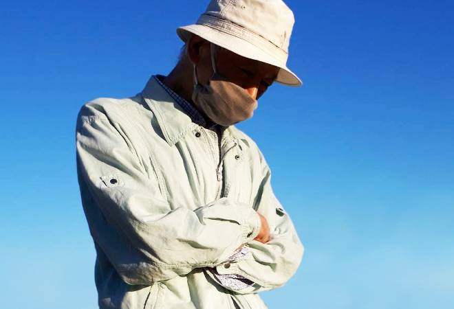 項垂れる農家の男性。